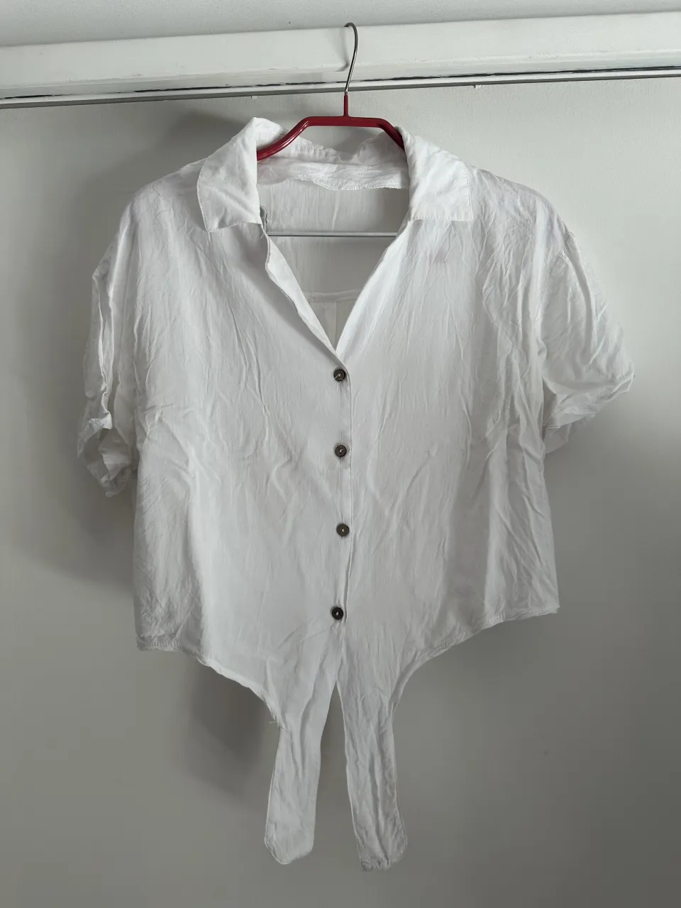 Camisa blanca de manga corta con botones y lazo delantero. Perfecta para un look casual y fresco.