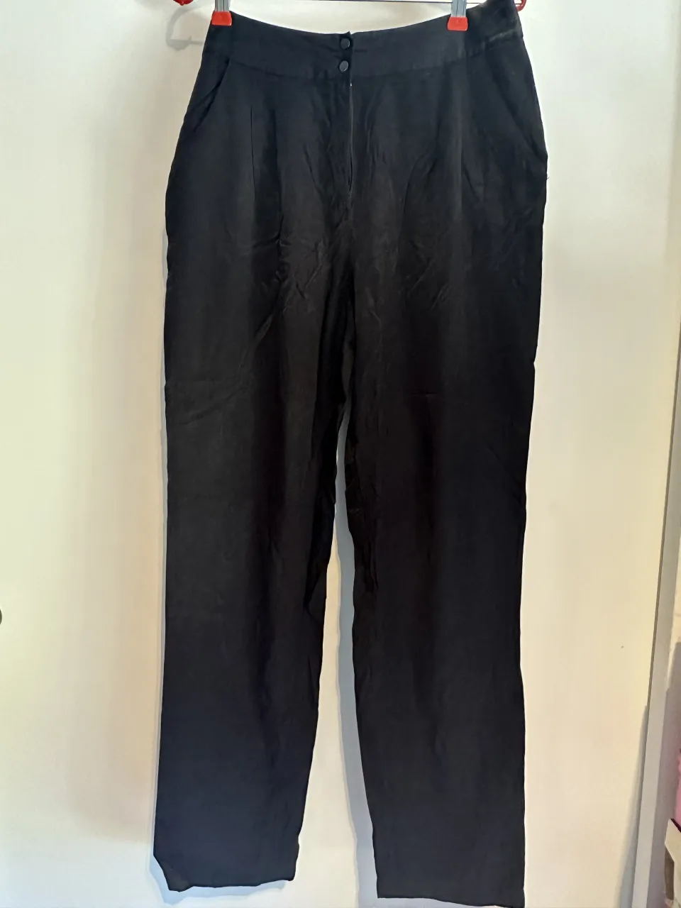 Pantalón negro de vestir, tiro alto, con dos botones en la cintura. Diseño elegante y moderno, ideal para un look sofisticado.