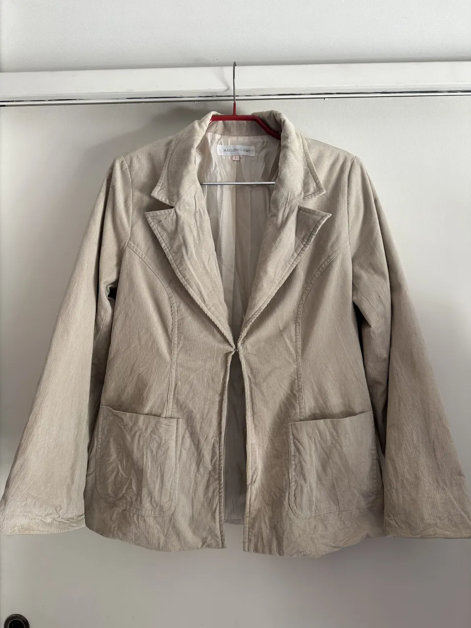 Blazer de corderoy color crudo, con solapas clásicas y bolsillos frontales. Una prenda versátil y elegante, ideal para completar cualquier look.