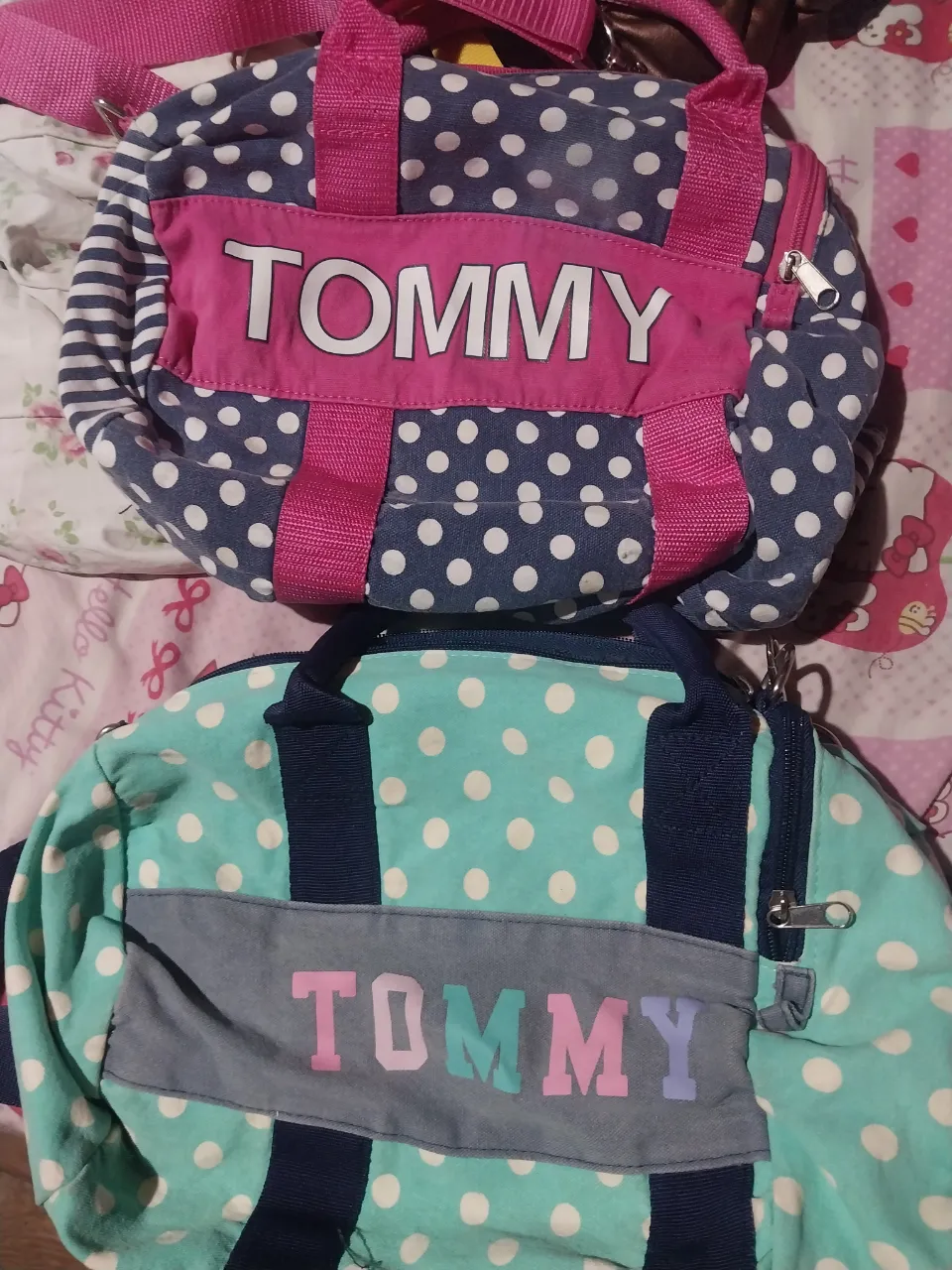 Set de dos bolsos "Tommy" con estampa de lunares y rayas. Uno en azul marino con lunares blancos y detalles en rosa, y otro en verde agua con lunares blancos y detalles en gris y colores pastel. Ideales para llevar lo esencial con estilo.