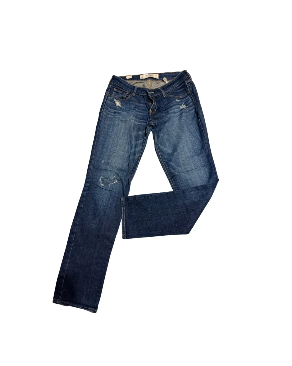 Jeans de denim azul con roturas y desgastes. Cierre de botón y cierre.