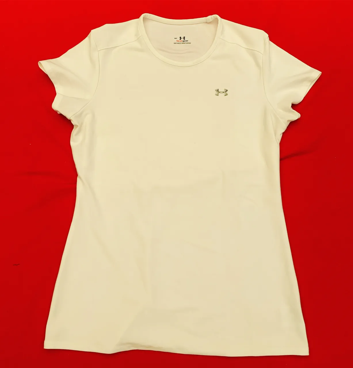 Remera deportiva color blanco con logo de Under Armour bordado en el frente.