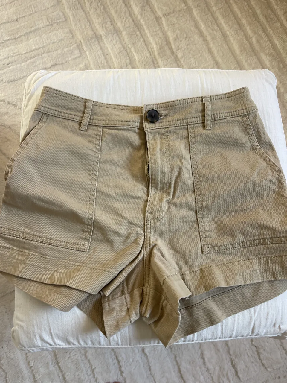 Shorts de gabardina color tiza con bolsillos delanteros y traseros. Cierre y un botón en la cintura.