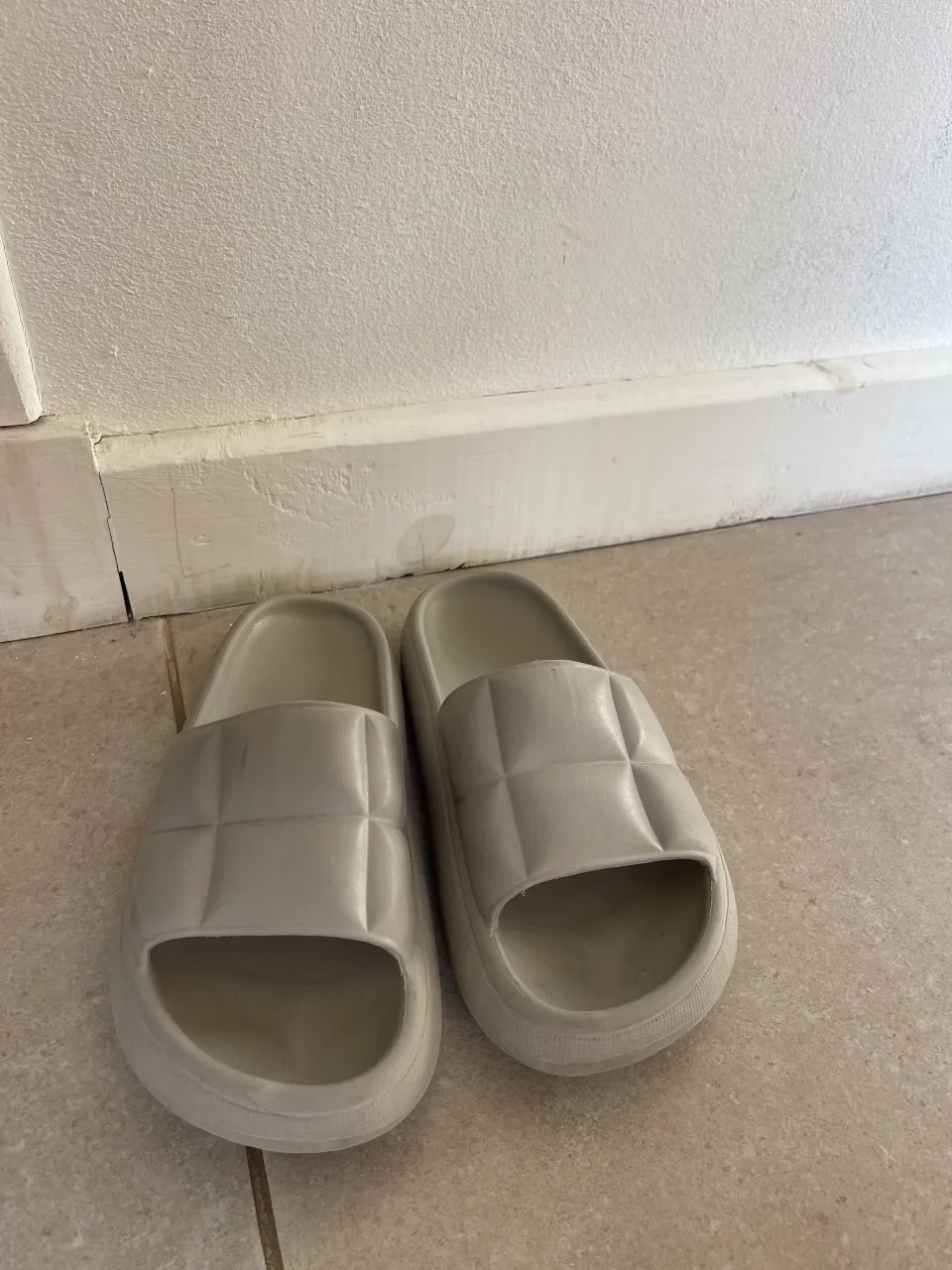 Ojotas de color gris claro, con tiras acolchadas y suela gruesa.