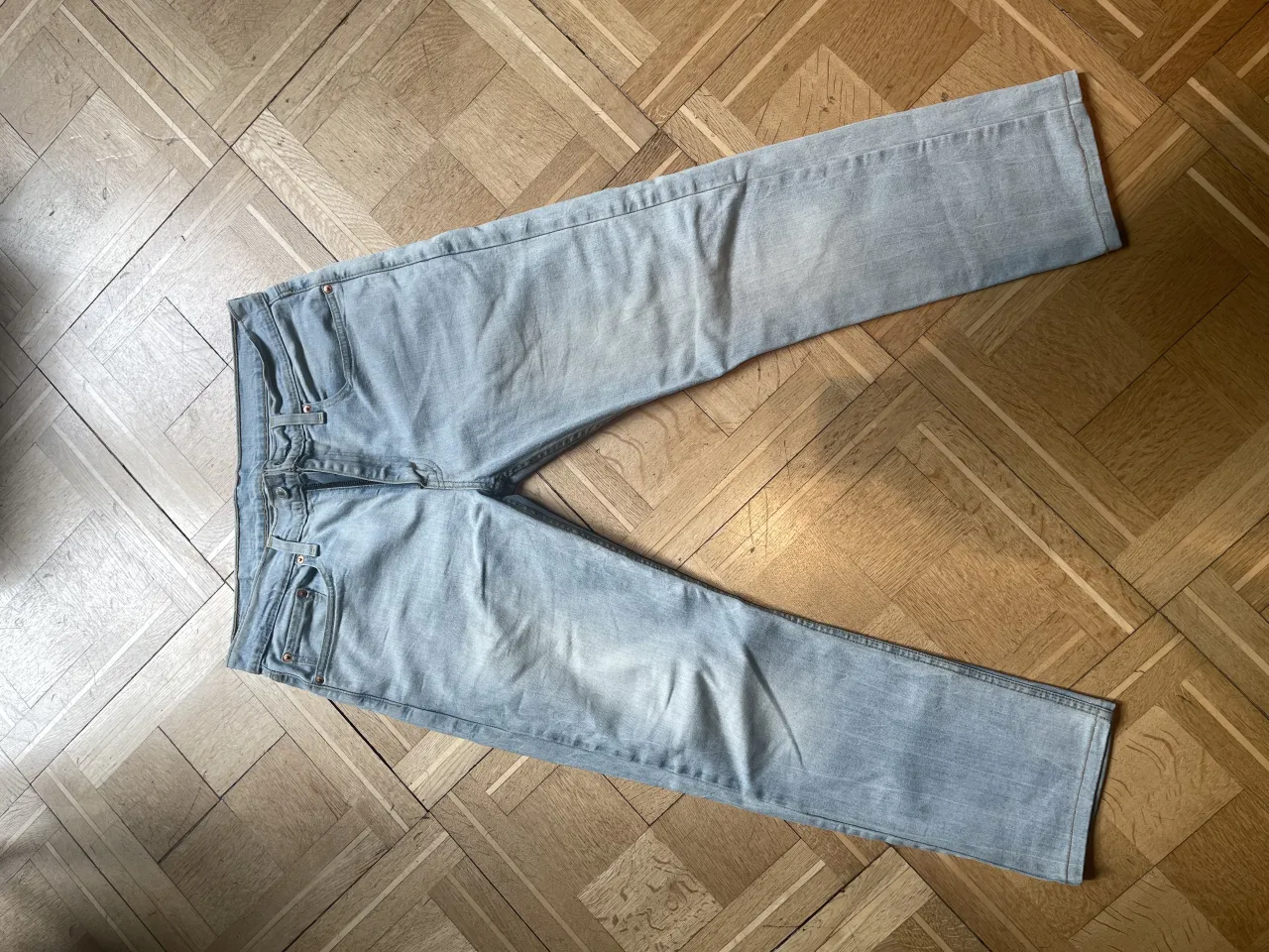 Jeans de algodón celestes, con bolsillos delanteros y traseros. Etiqueta de marca visible en la parte trasera.