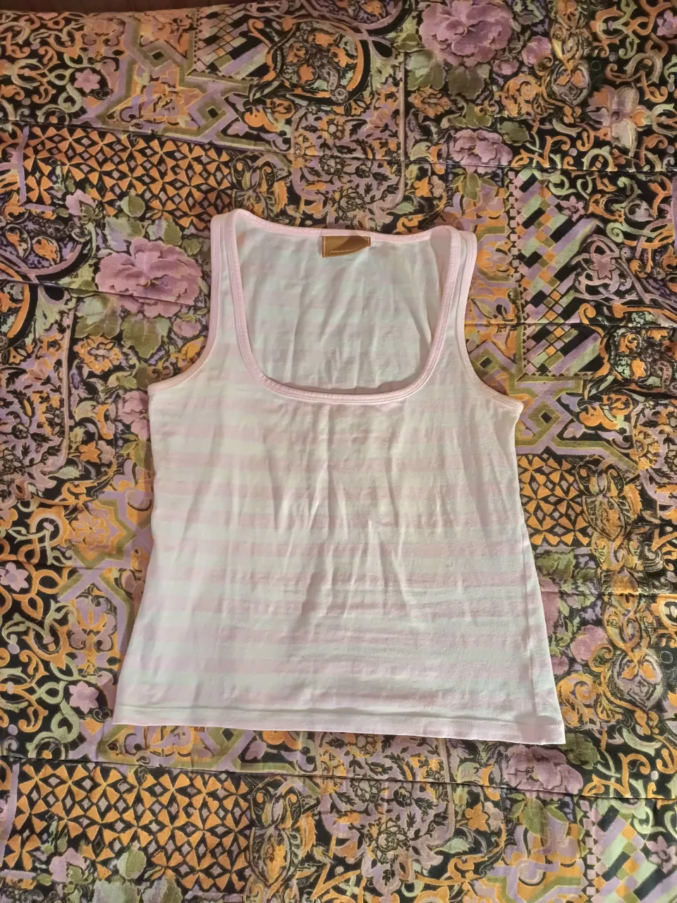 Musculosa a rayas finas blancas y rosas. Tiene detalles en color rosa en el cuello y los hombros.