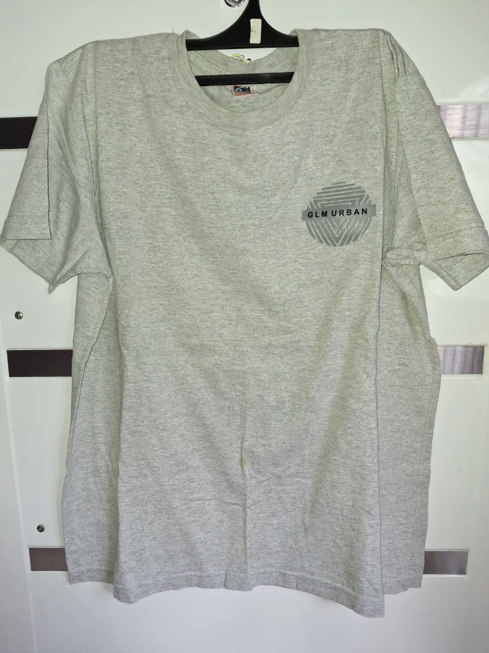 Remera gris de manga corta con estampa circular en el frente que dice "GLM URBAN".