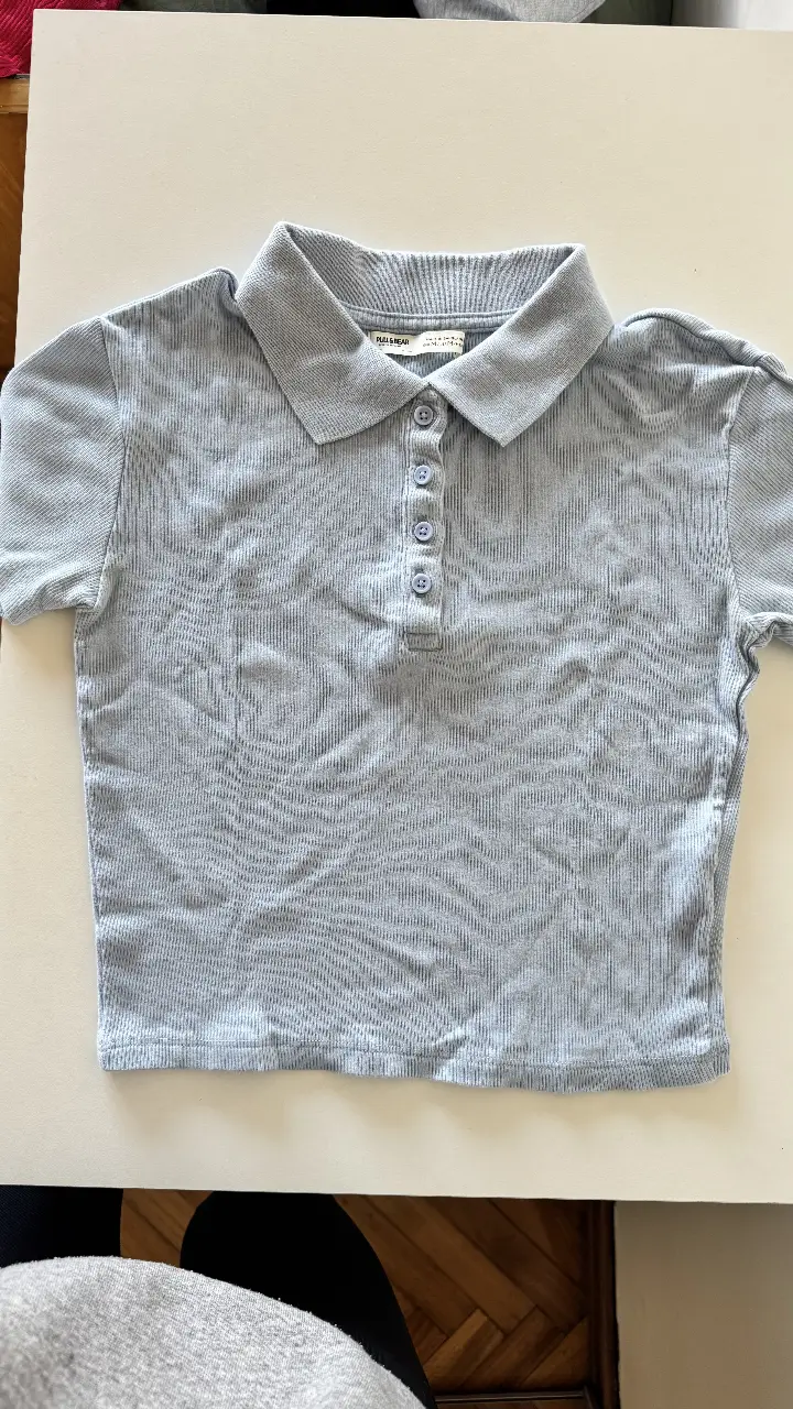 Remera de mujer celeste, de tejido acanalado, con cuello polo y botones. Ideal para un look casual y moderno.