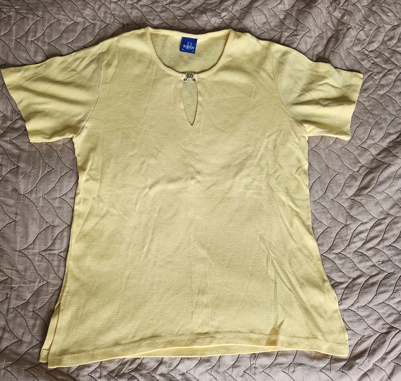 Remera amarilla de manga corta con escote en V y detalle metálico en el cuello. 
Talle 4 tela de algodón 