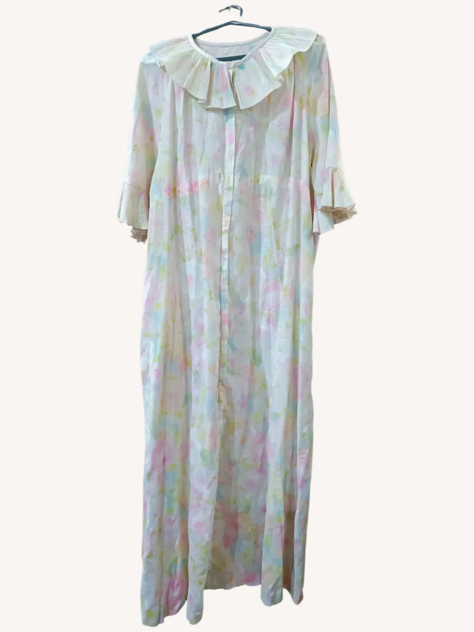Vestido largo vintage con estampado floral en tonos pastel. Posee un cuello con volados plisados y mangas con terminación acampanada y volados. Ideal para un look romántico y delicado. Tiene cierre delantero. Falta un cordoncito que llevaba en la cintura.