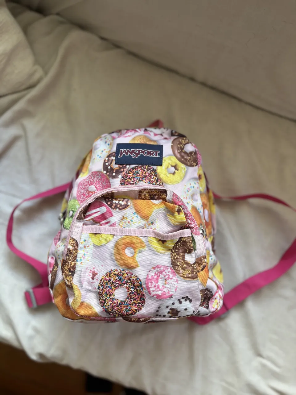Mochila Jansport súper linda y original con estampa de donas. Ideal para el día a día, la escuela o para llevar tus esenciales con un toque divertido. ¡No te la pierdas!