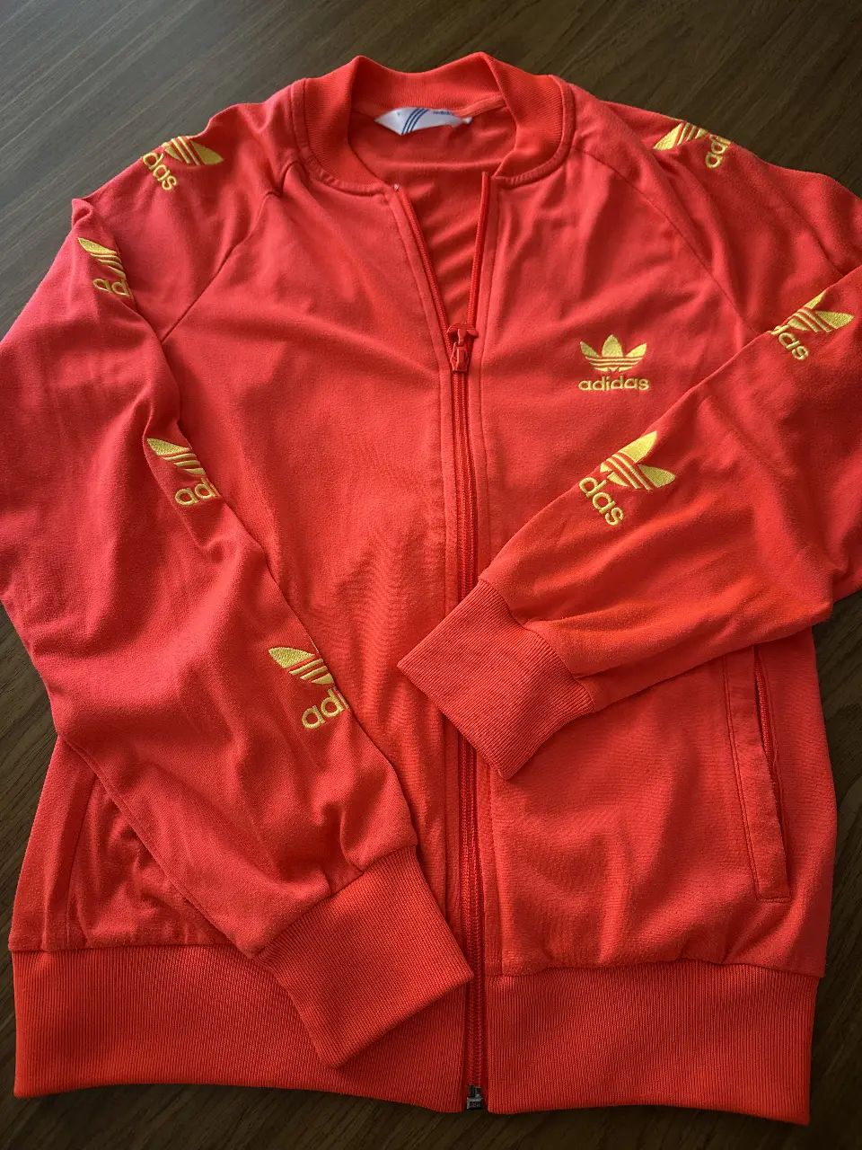 Buzo deportivo Adidas rojo con detalles dorados. Ideal para un look retro y cómodo. Con cierre frontal y el logo icónico de la marca.