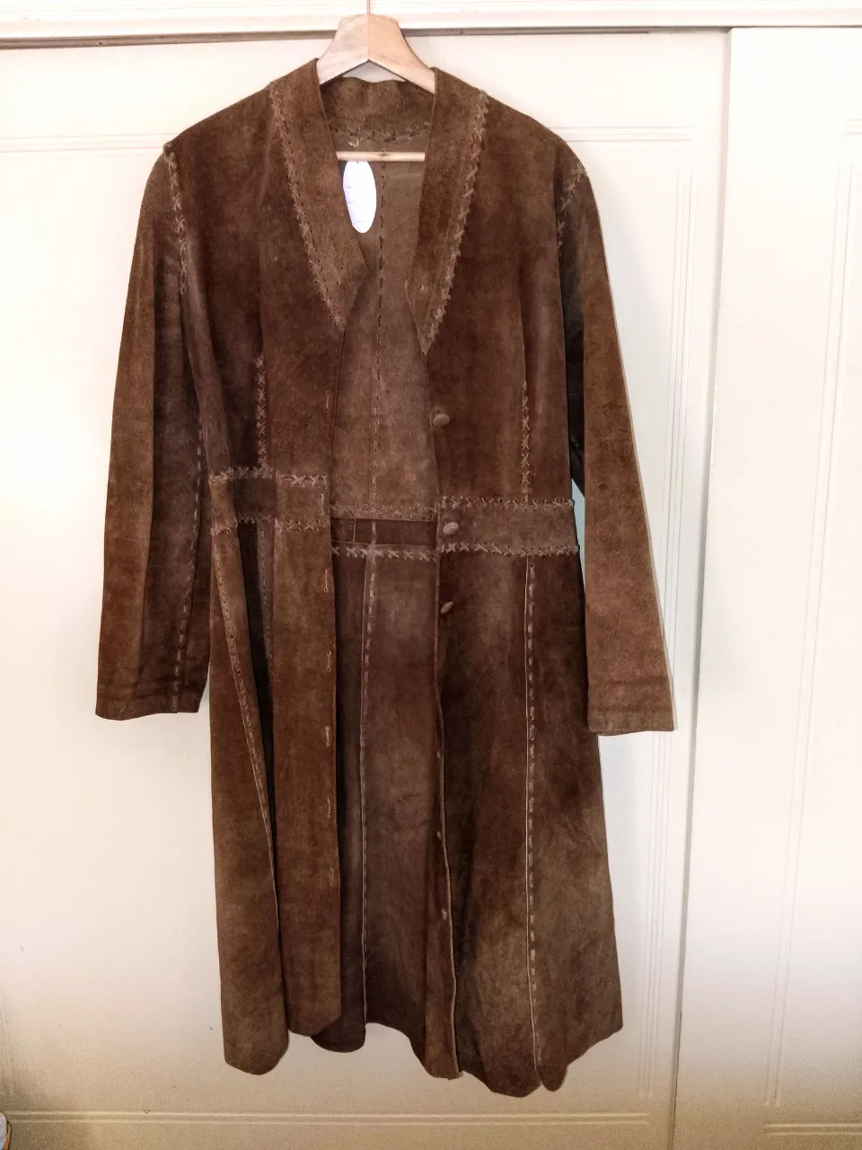 Campera larga de gamuza marrón con detalles de costura y trenzado en los bordes y cintura. Posee botones al frente.Le falta los botones de abajo (tiene botones hasta la mitad, cintura) 