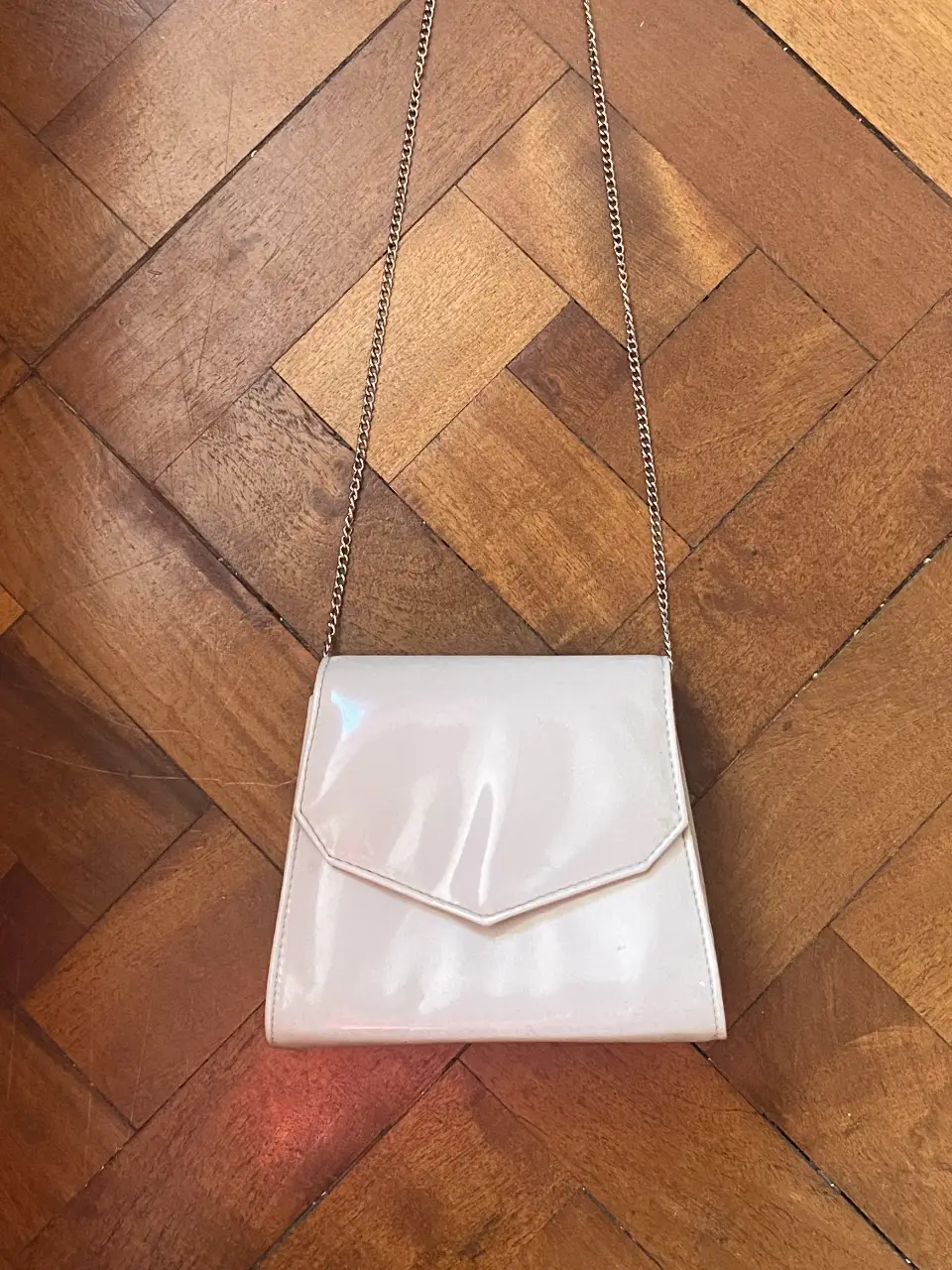 Cartera de mano color hueso con cadena plateada. Ideal para salidas y fácil de combinar. Se cierra con botón imantado y tiene un bolsillo interno. Muy pocos usos.