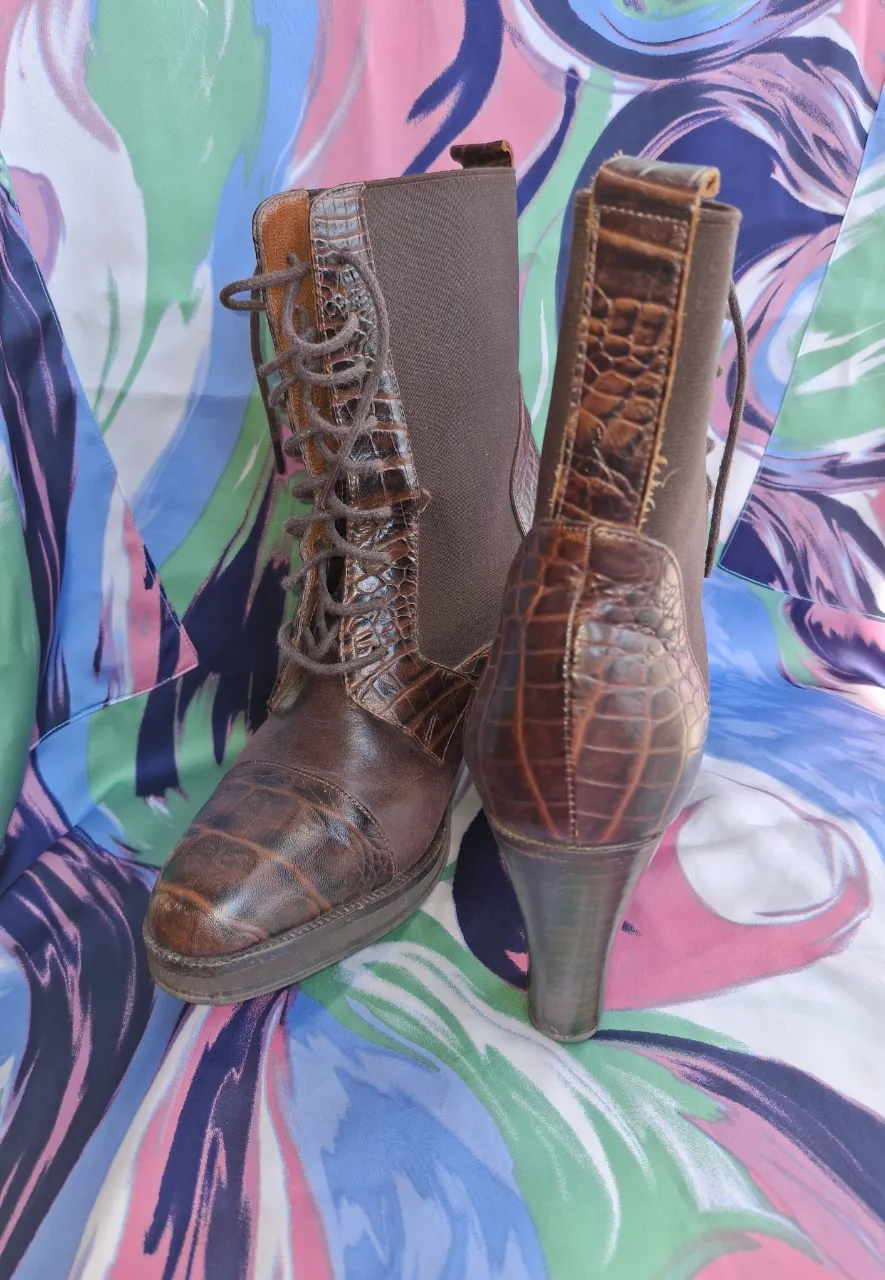 Botas de cuero marrón con textura de cocodrilo y cordones al frente. Detalle de elástico en la parte superior trasera.