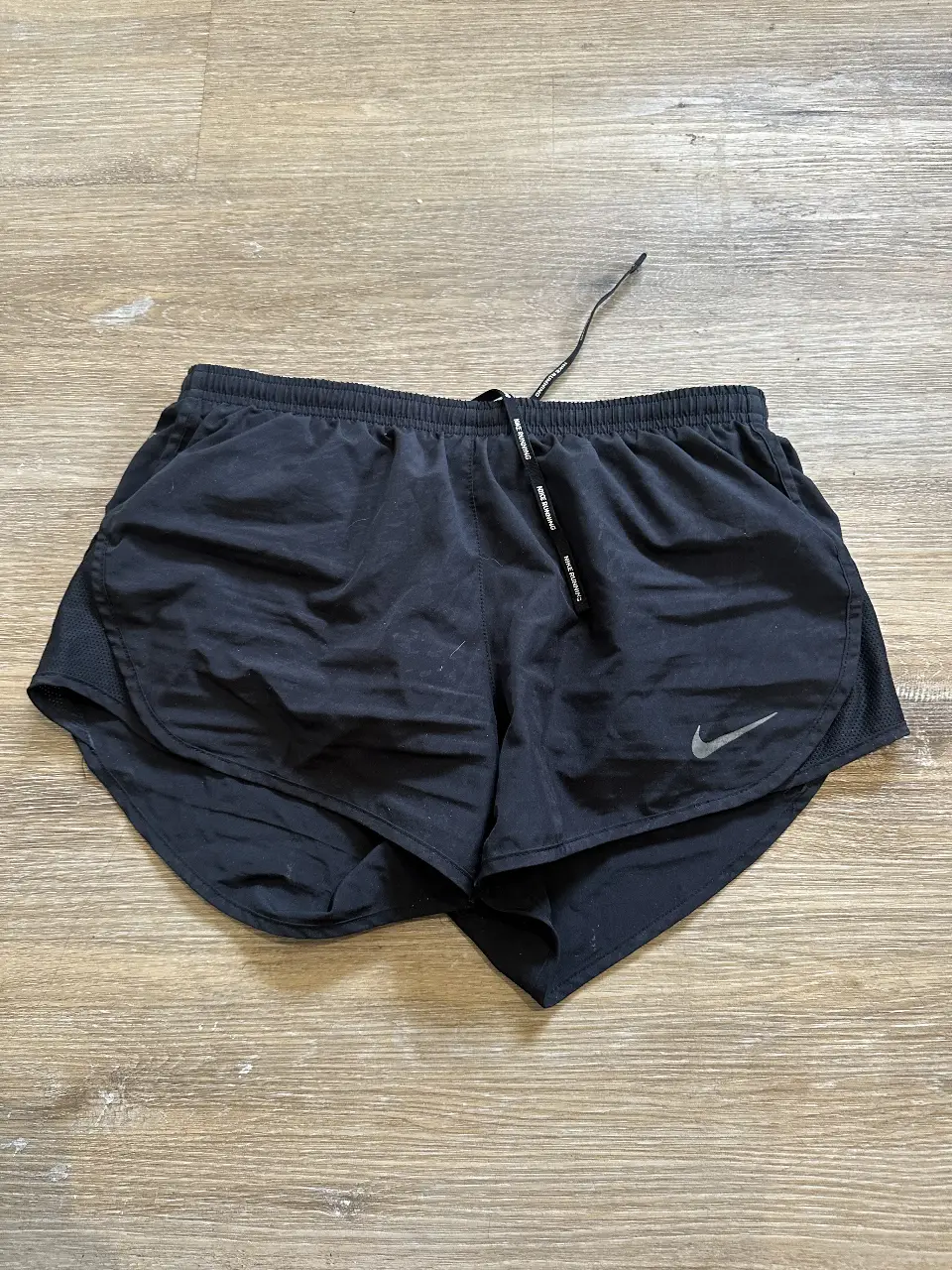 Short deportivo Nike para running, color negro, con logo de la marca en gris. Ideal para entrenamientos y actividades al aire libre.