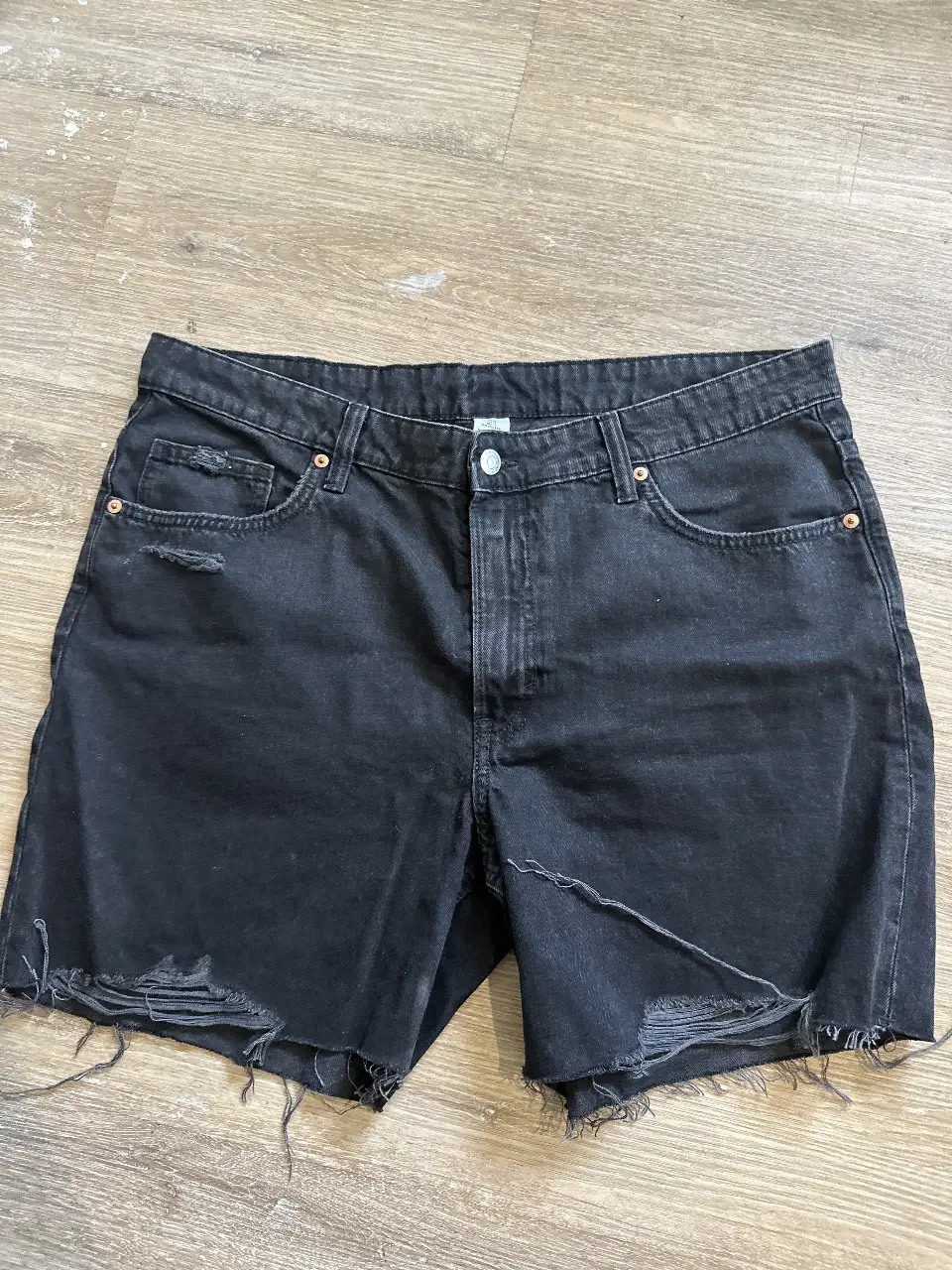 Short de jean negro de mujer, tiro alto, con detalles de roturas en el frente y flecos en el borde inferior. Ideal para un look casual y moderno. Talle XL