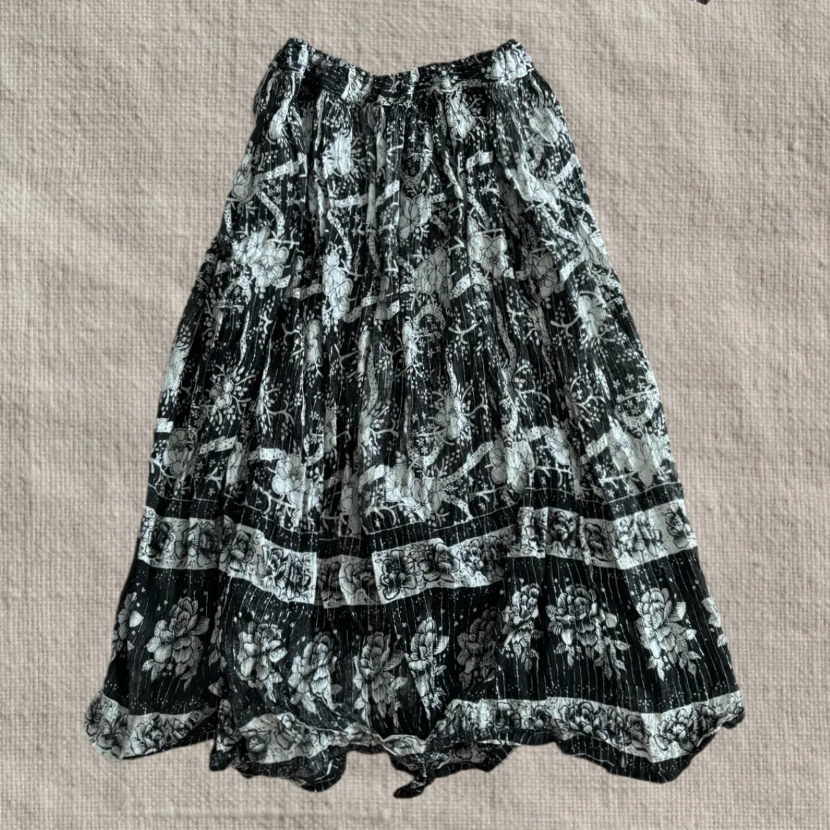 Pollera larga estampada con flores y detalles geométricos. Cintura elastizada. Tiene hilos plateados que brillan.