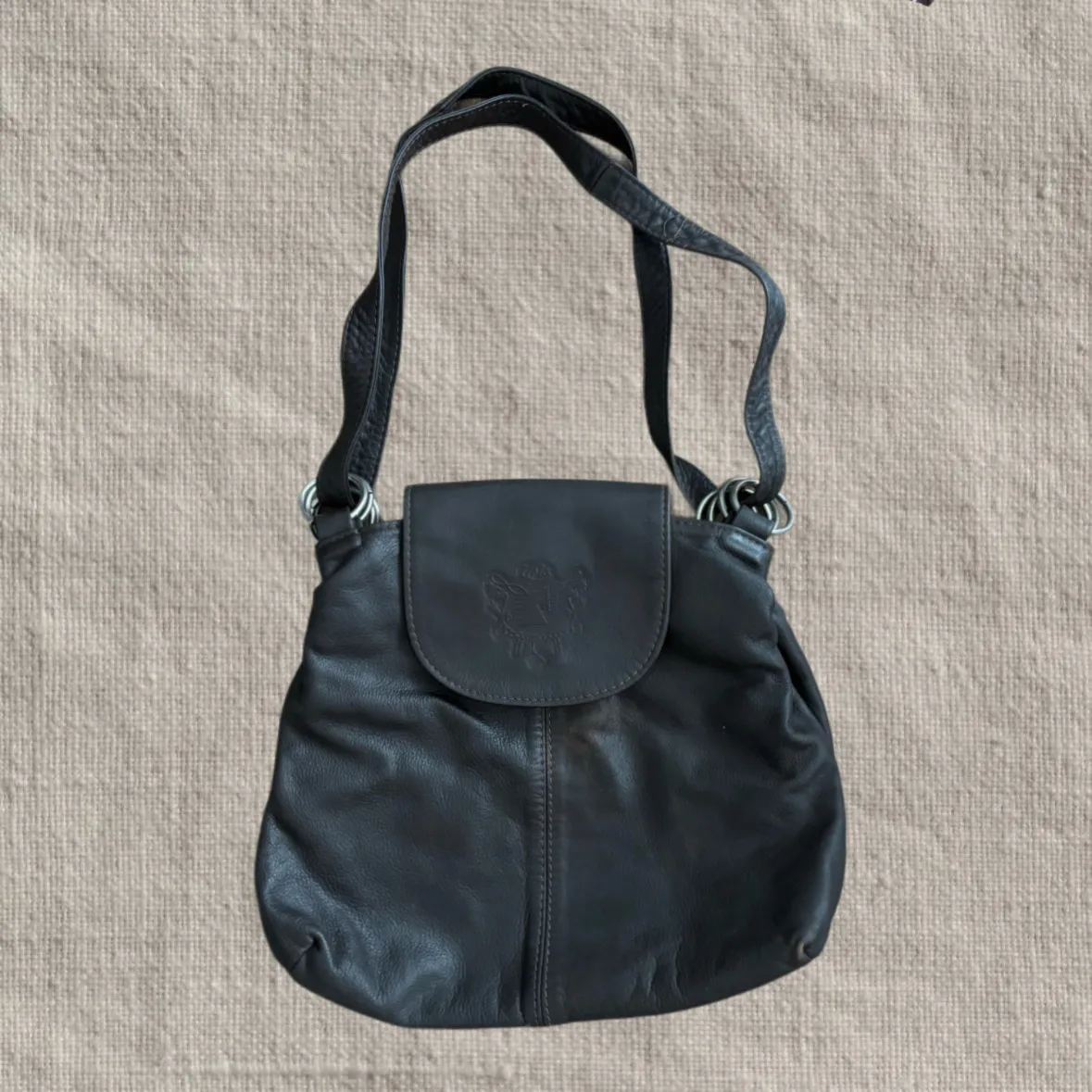 Cartera de cuero marrón con aros en la correa.