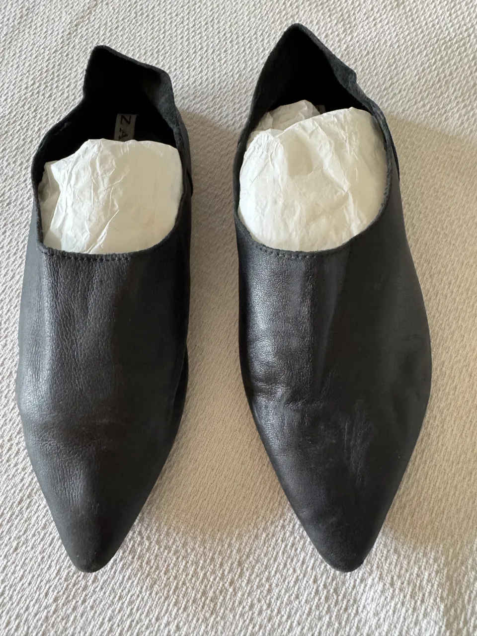 Zapatos negros de cuero con punta fina y escote pronunciado.