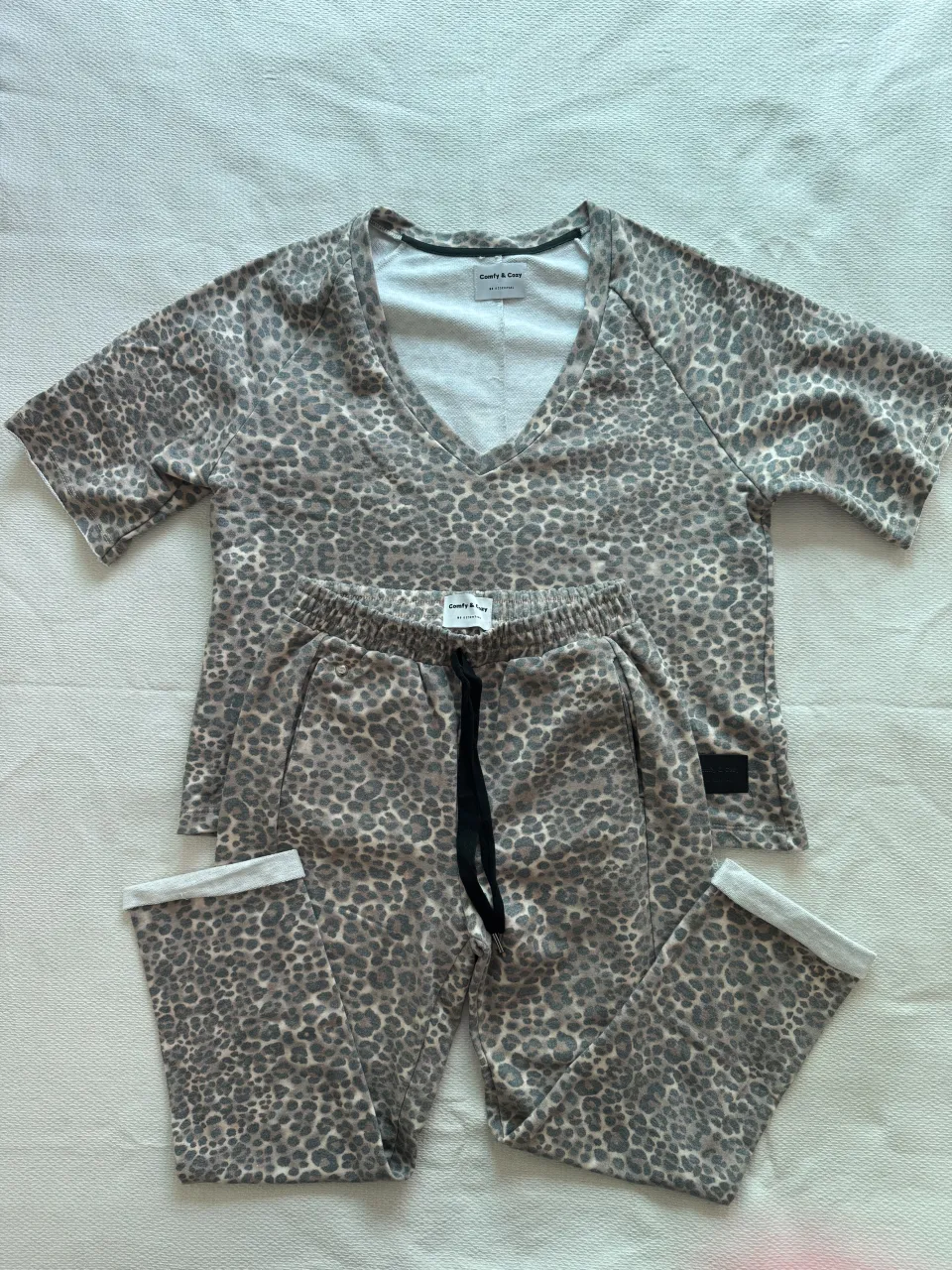 Conjunto de pantalón y remera con estampa de leopardo. La remera es de manga corta y escote en V. El pantalón es largo con cintura elastizada y cordón.