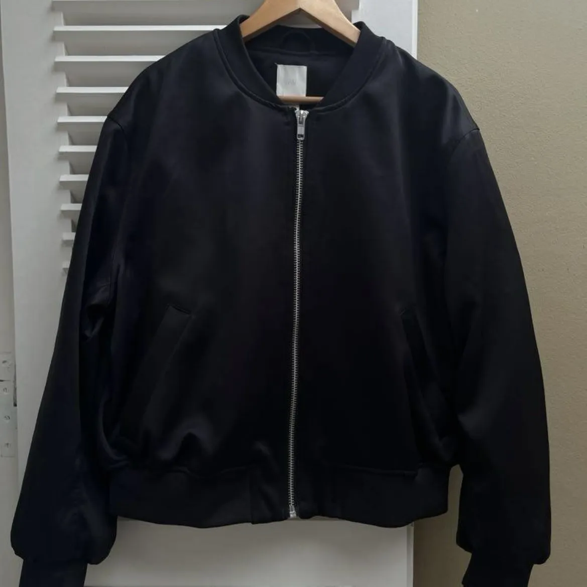 Campera bomber negra con cierre metálico central y cuello, puños y cintura elastizados