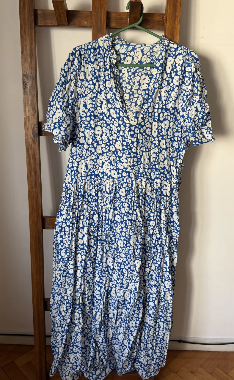 Vestido largo estampado en azul y blanco, con volados en el cuello y mangas cortas. Ideal para un look fresco y femenino. Detalles: manchas - ver fotos