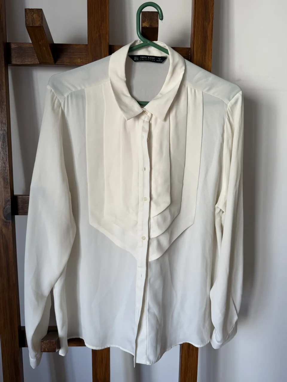 Camisa blanca de vestir con detalles plisados en el frente. Manga larga y cuello clásico. Perfecta para un look elegante y formal.