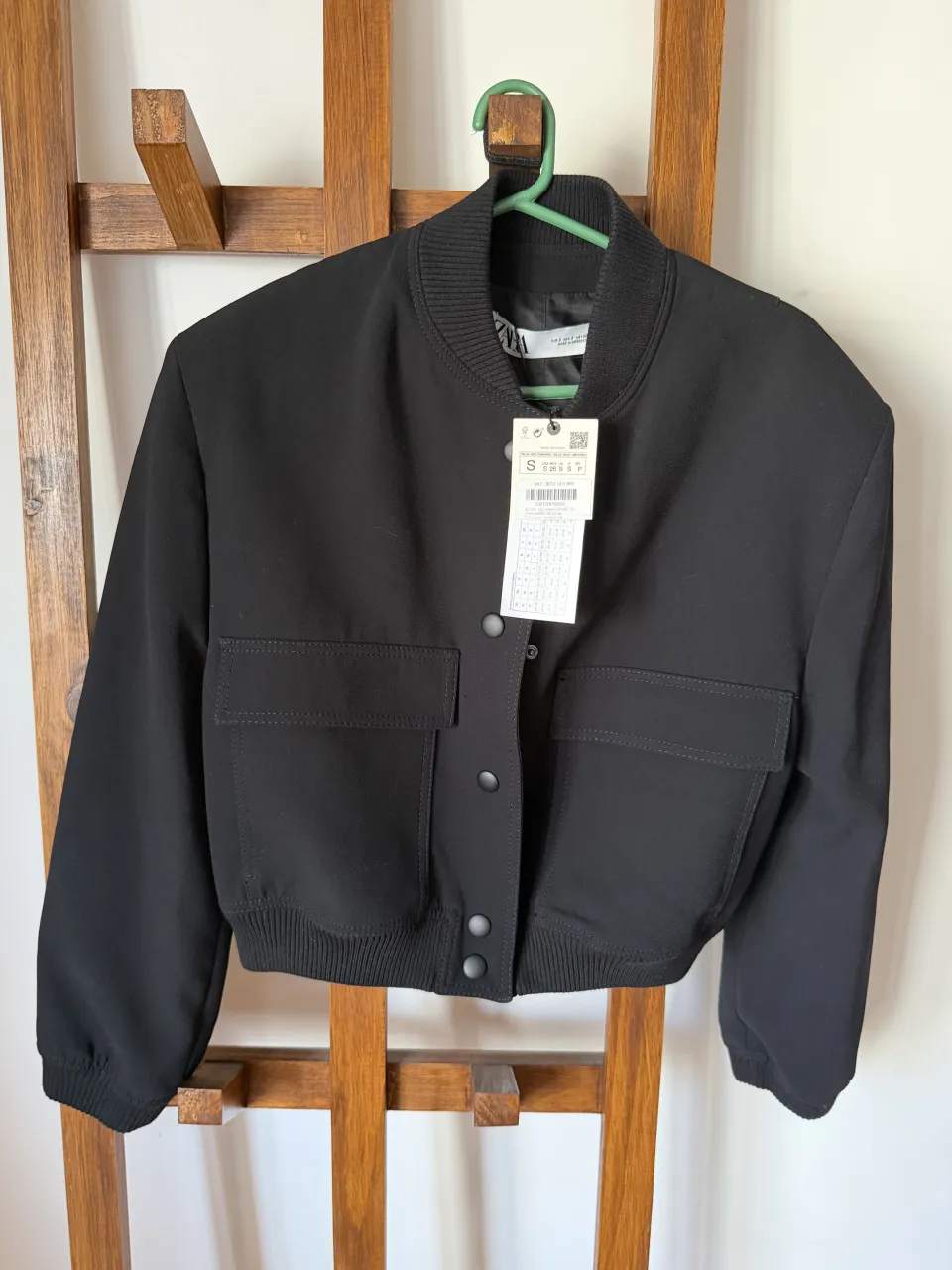 Campera bomber negra corta, con bolsillos frontales y puños elastizados. Ideal para un look casual y moderno.