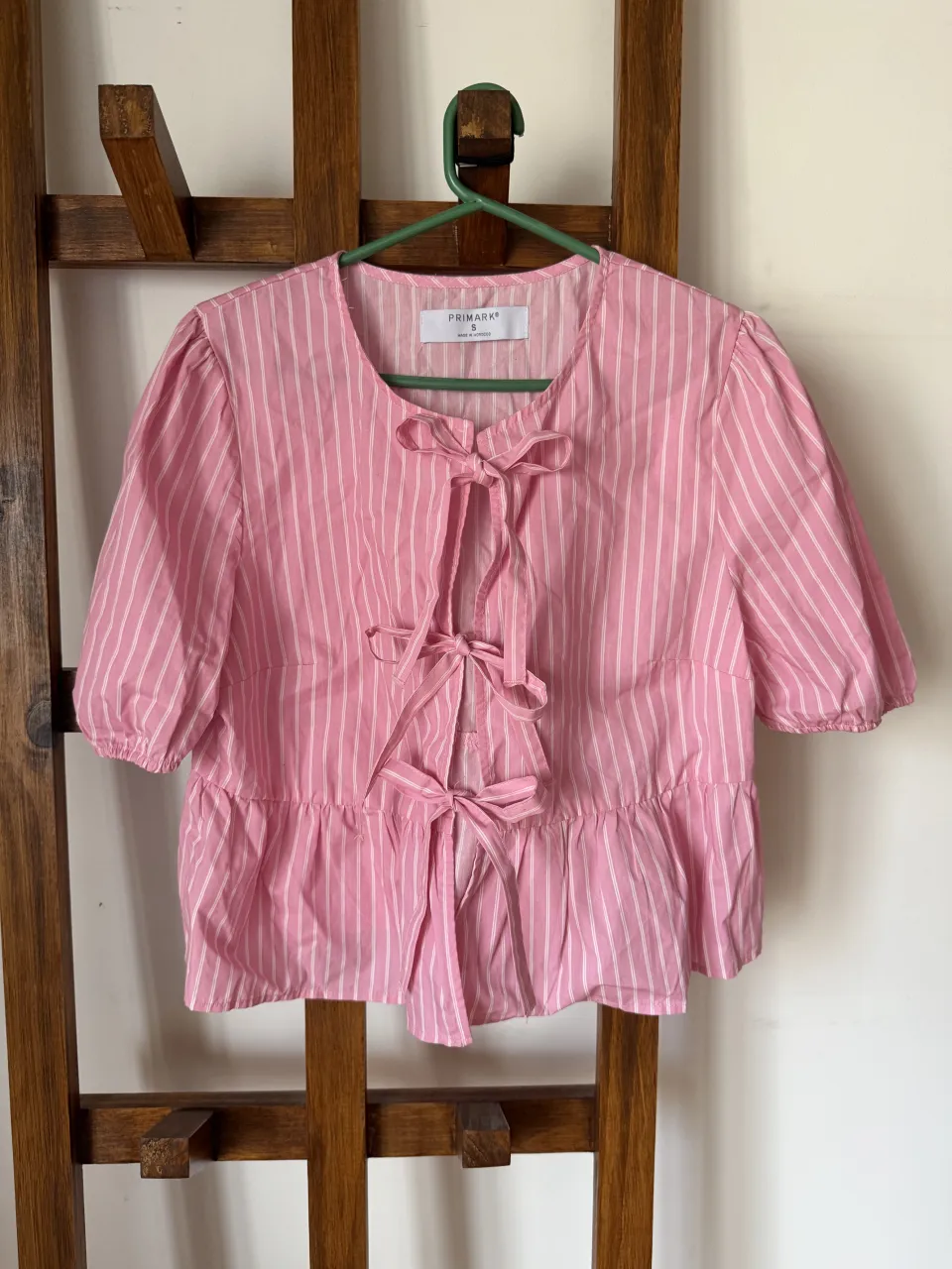 Blusa rosa a rayas blancas con volados y lazos en el frente. Mangas cortas abullonadas con elástico. Ideal para un look canchero y femenino.