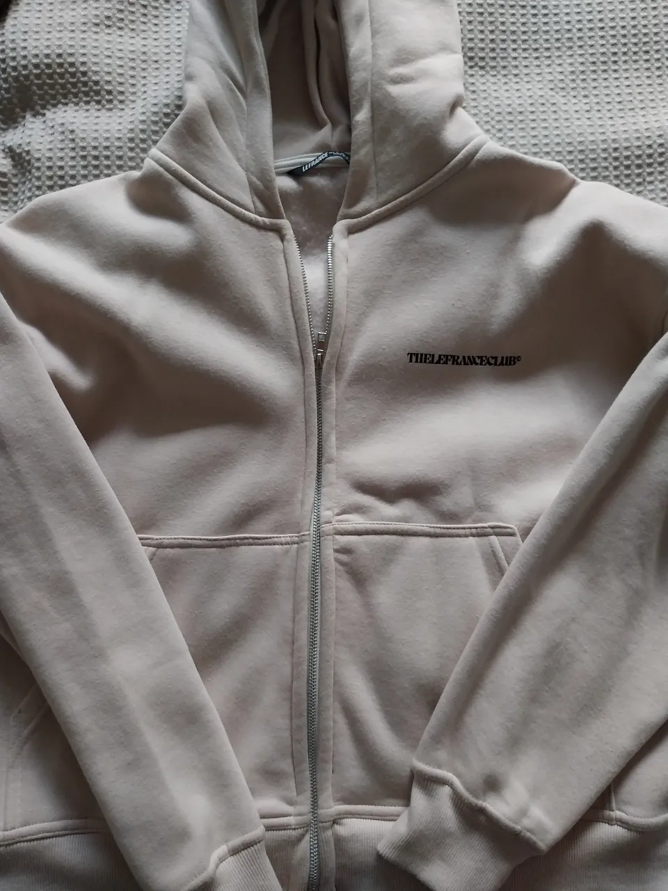 Buzo con capucha y cierre completo. Estampa de logo en la espalda y en el frente.