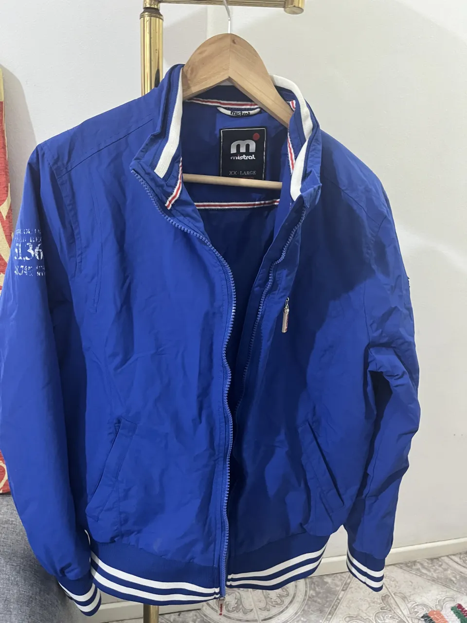 Campera azul vibrante, ideal para un look casual y deportivo. Posee detalles de franjas blancas en puños y cintura, y un cuello estilo bomber. Perfecta para días frescos de primavera u otoño.