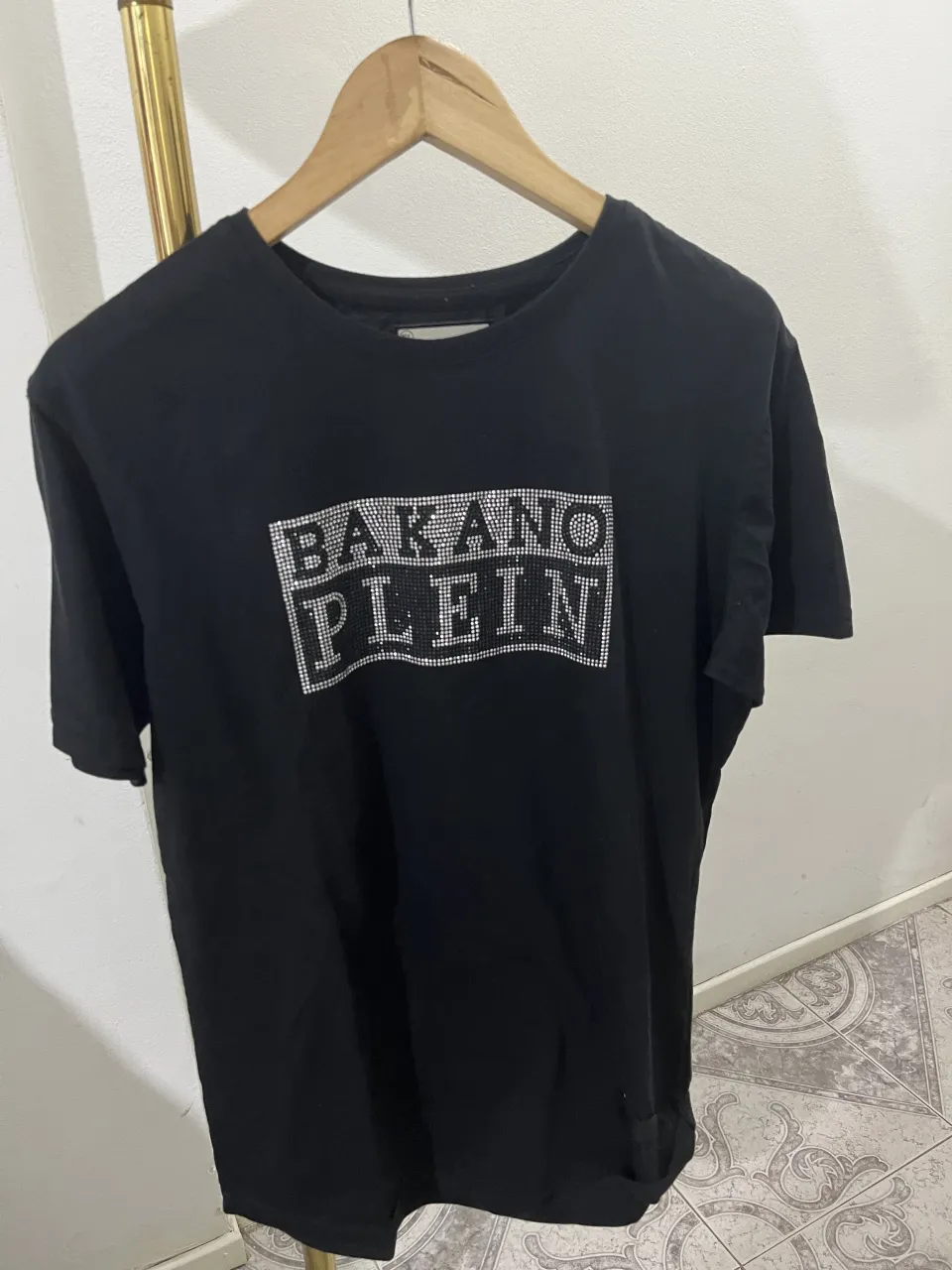 Remera negra de manga corta con estampa "BAKANO PLEIN" en strass plateado. Un diseño llamativo y moderno, ideal para un look urbano y canchero.