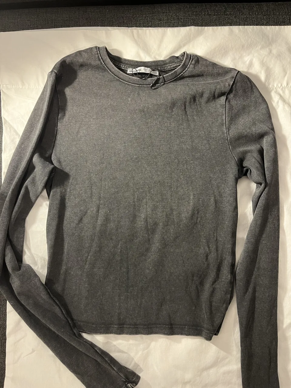 Remera gris de manga larga con cuello redondo.