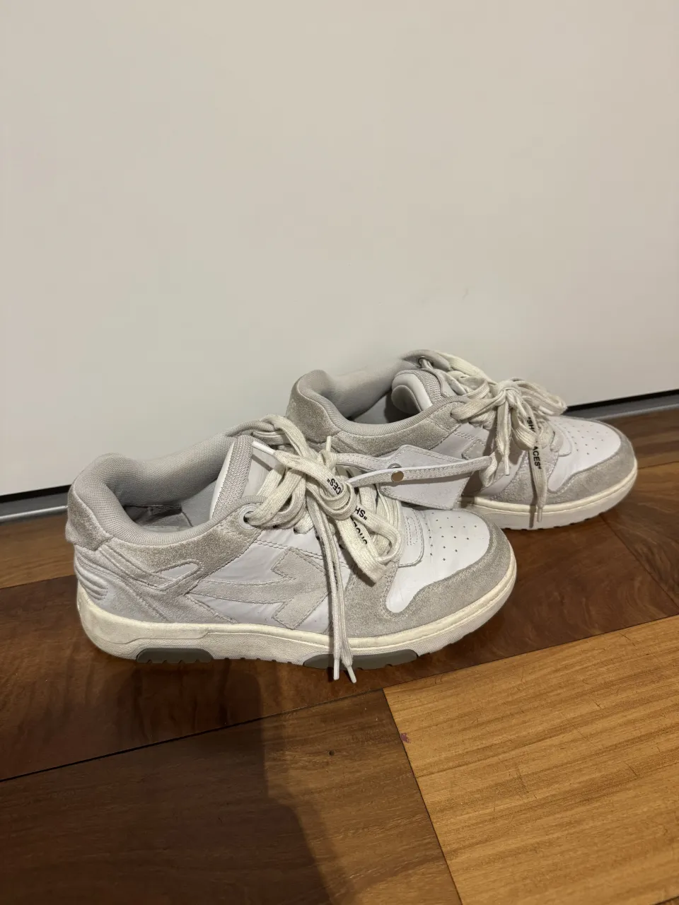 Zapatillas deportivas de cuero y gamuza en color blanco y gris. Cordones blancos y suela de goma.