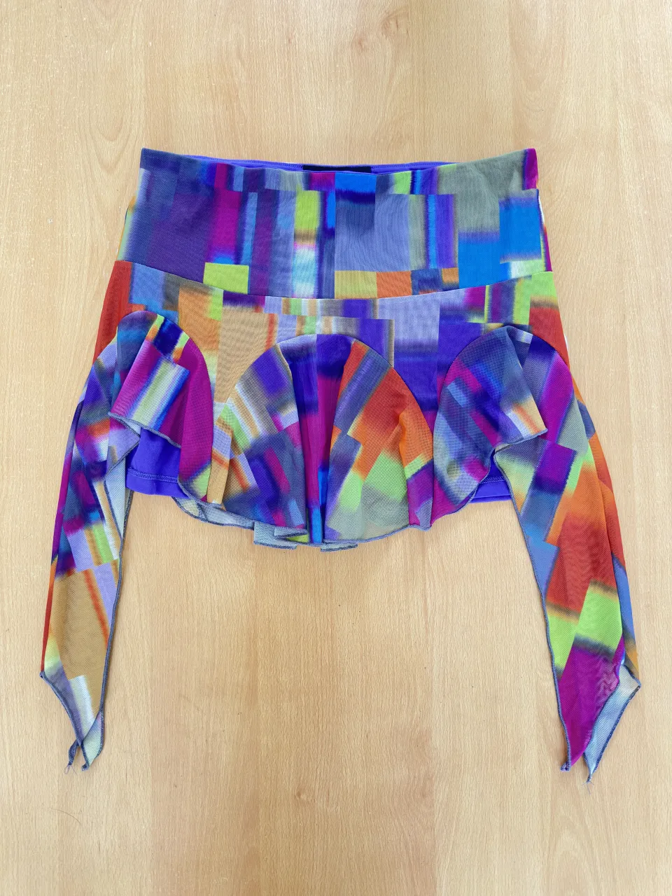 Pollera corta con estampado abstracto multicolor y detalles de volados. Ideal para un look vibrante y divertido.