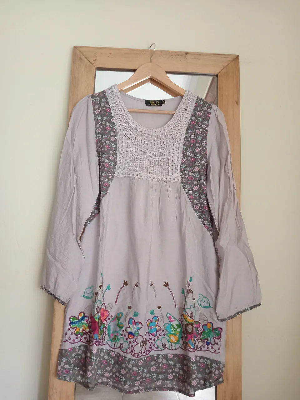 Remera manga larga de algodón color crudo con detalles de flores bordadas en la parte inferior y en los laterales del cuello. Posee un detalle de crochet en el escote y un estampado floral en la parte inferior y en los puños.Medidas 40 de hombro, 50 de sisa, 85 de largo.