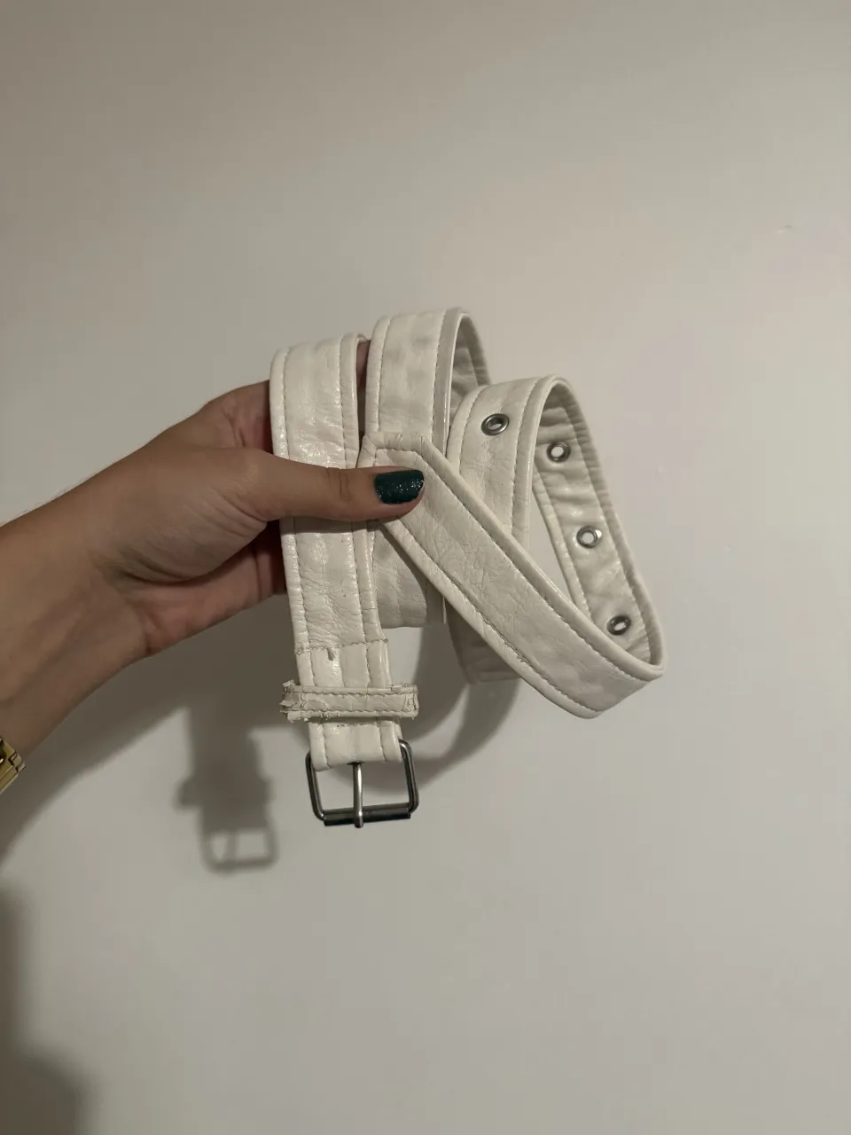 Cinturón blanco con hebilla plateada y múltiples ojales. LARGO APROX 115cm