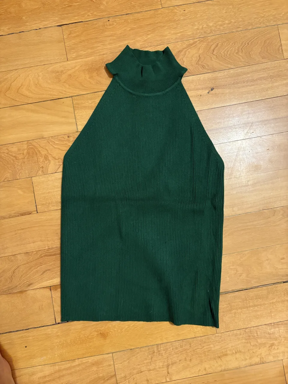 Top tejido de cuello alto y sin mangas, color verde oscuro. Ideal para un look canchero y moderno.