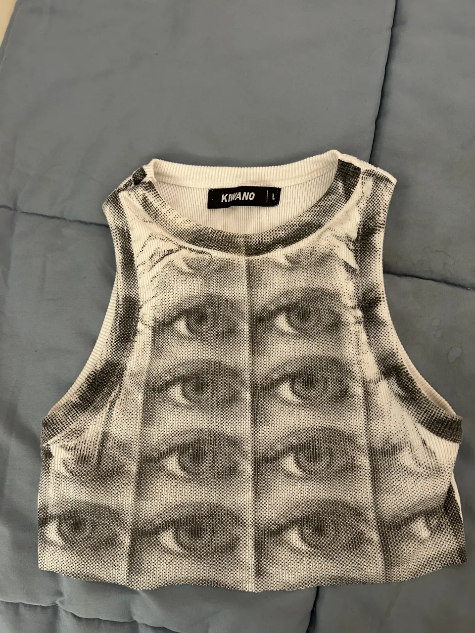 Musculosa blanca con estampa de ojos en blanco y negro. Tiene cuello redondo y es sin mangas. Talle L CHICO
