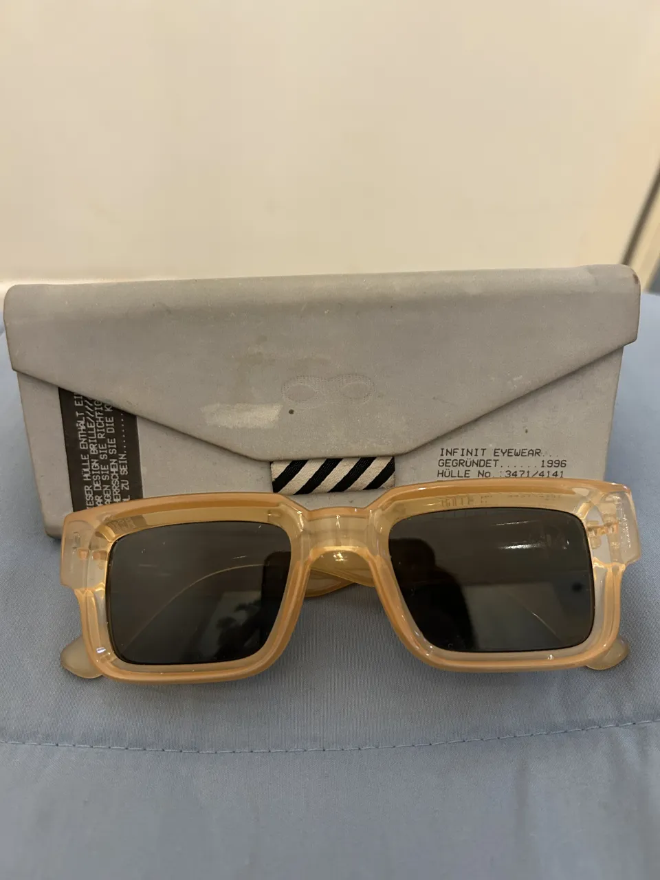 Lentes de sol  marca Infinit. con armazón translúcido color durazno y cristales oscuros. Incluyen estuche.