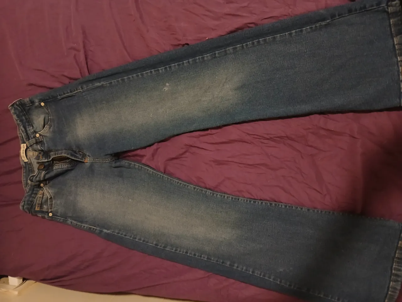 Jeans de tiro medio con detalles de desgaste y costuras a la vista. Cierre y botón en la parte delantera. Talle 42. Tiene unas manchitas blancas en la parte de adelante, pero esta aceptable. 