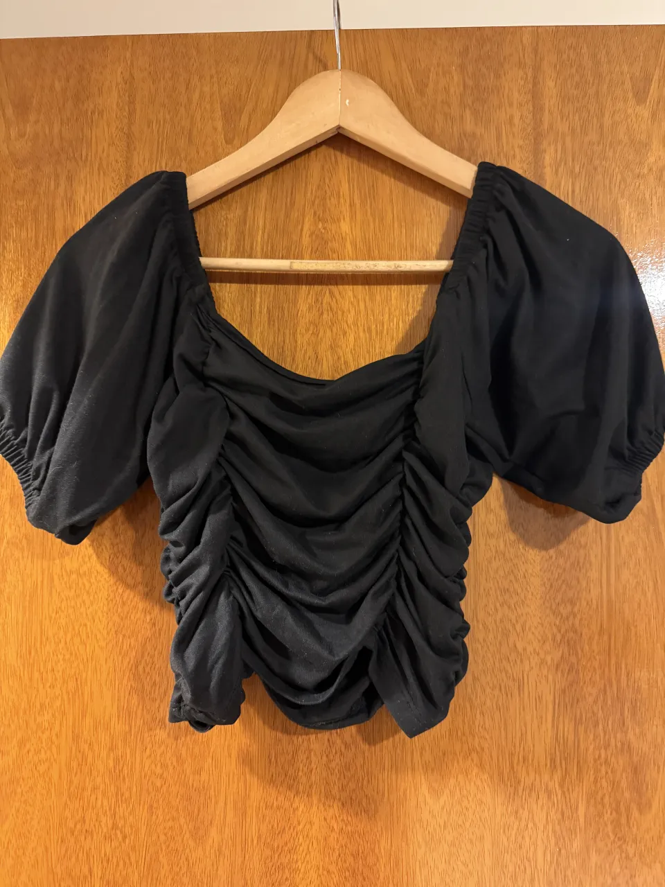 Top negro con fruncido delantero y mangas abullonadas.