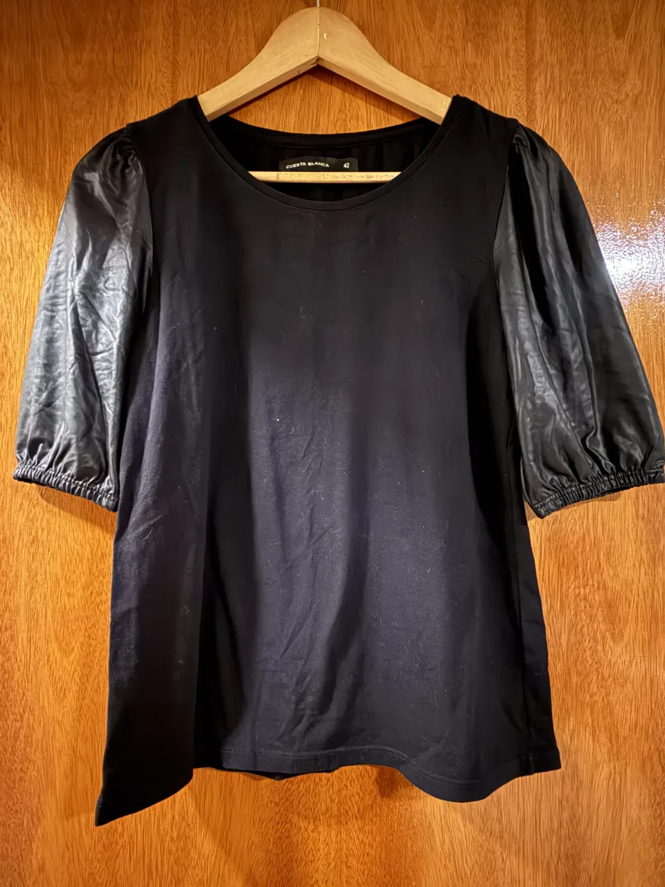 Remera negra de manga corta con mangas abullonadas de efecto cuero.