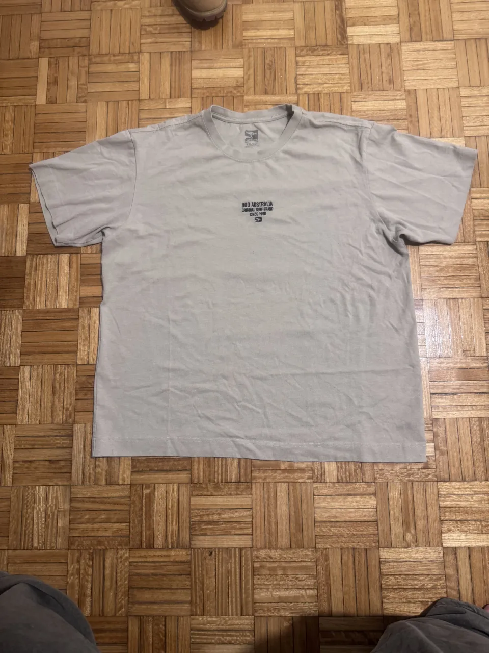 Remera de algodón color tiza, con estampa "DOO AUSTRALIA ORIGINAL SURF BRAND SINCE 1998" en el frente. Ideal para un look casual y relajado.