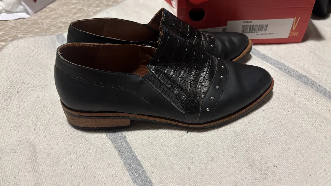 Zapatos negros de cuero con detalle de textura de cocodrilo y tachas. Cierre lateral para facilitar el calce. Ideales para un look canchero y moderno.