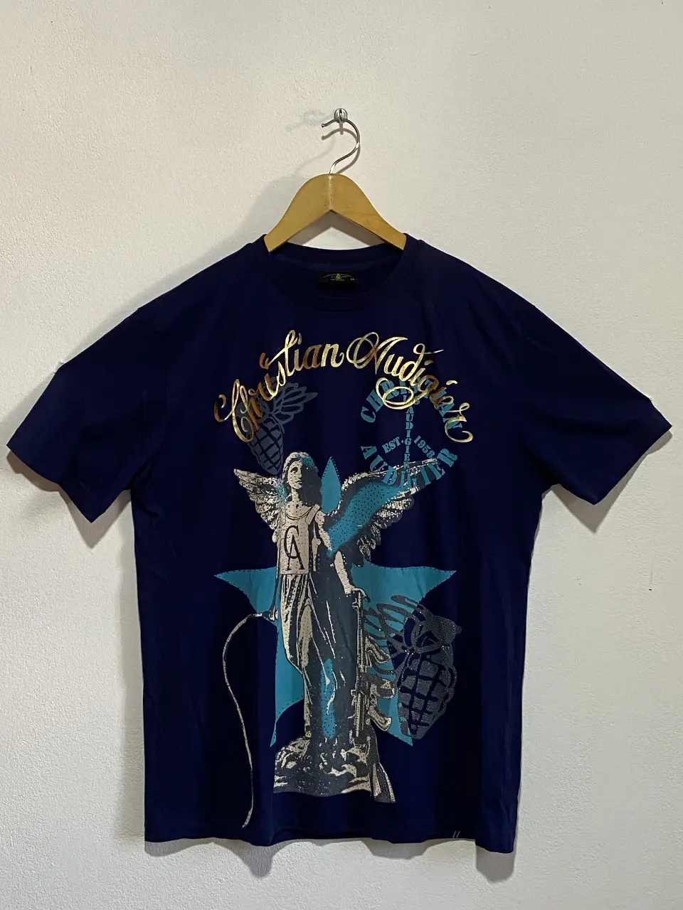 Remera de hombre Christian Audigier, azul marino con estampado frontal y trasero. Diseño con ángel y detalles dorados. Talle XL.