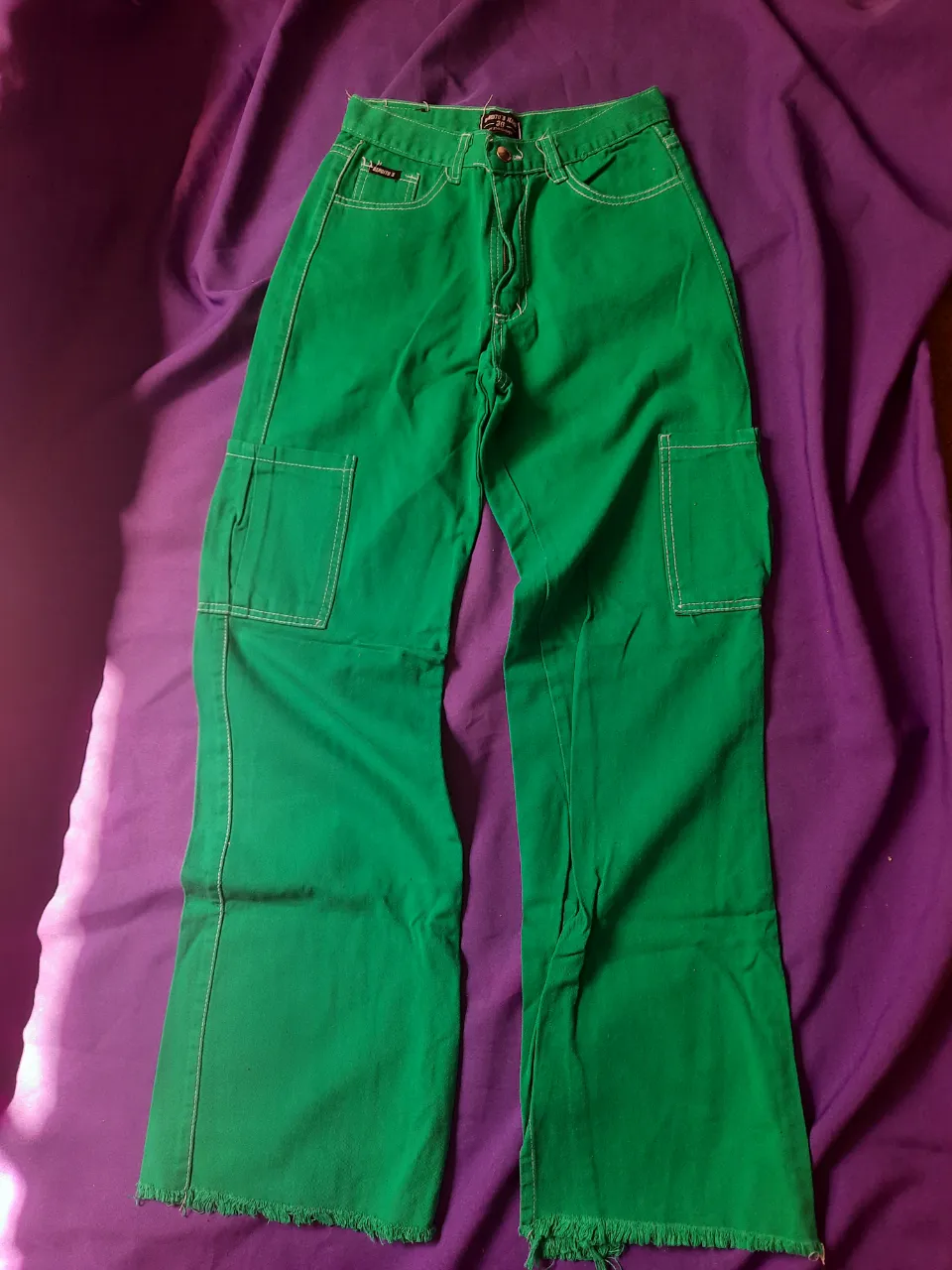 Jean wide leg cargo de color verde. Posee bolsillos laterales con tapa y costuras blancas. El bajo del pantalón es desflecado y tiene una abertura lateral. Talle 36.