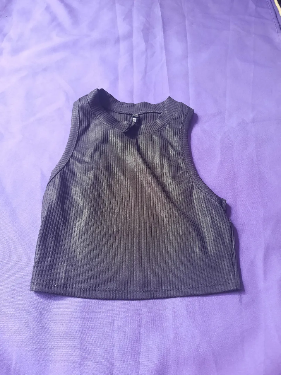 Musculosa negra acanalada con cuello redondo. Es brillosa y tipo top.