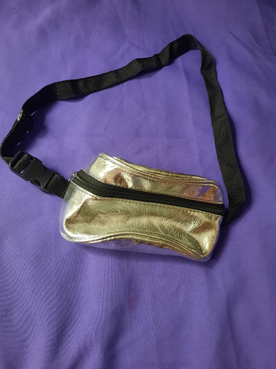 Riñonera plateada con cierre negro y correa ajustable. 